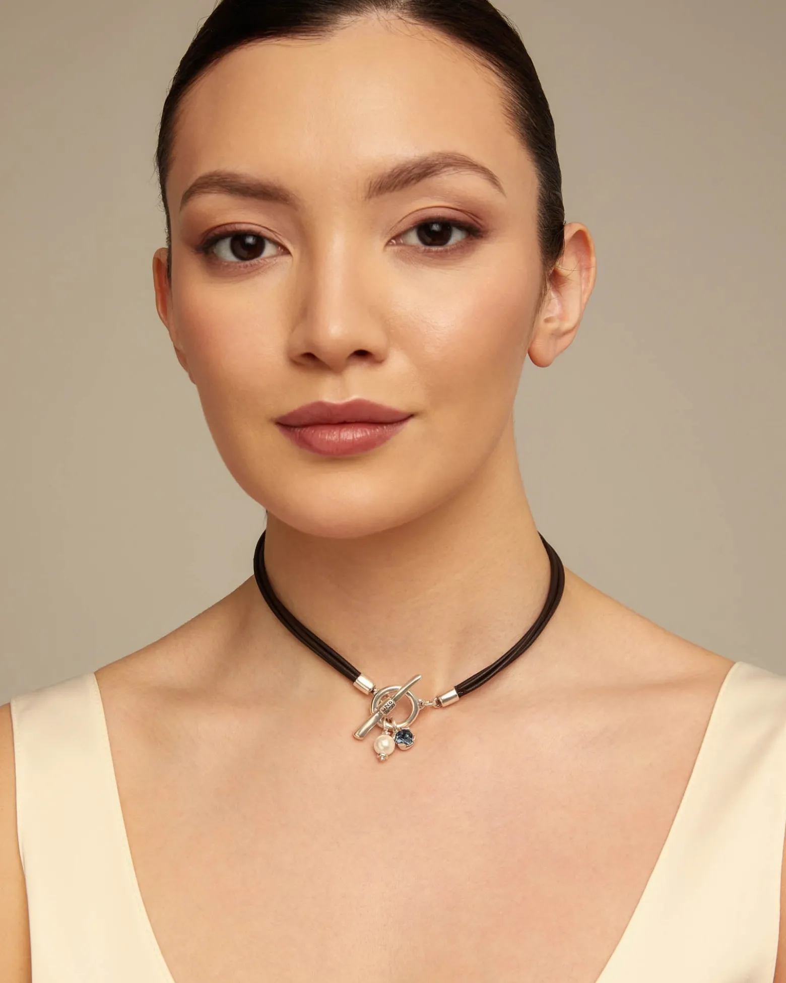 Collar de cuero con cierre central con charm de perla y cristal.