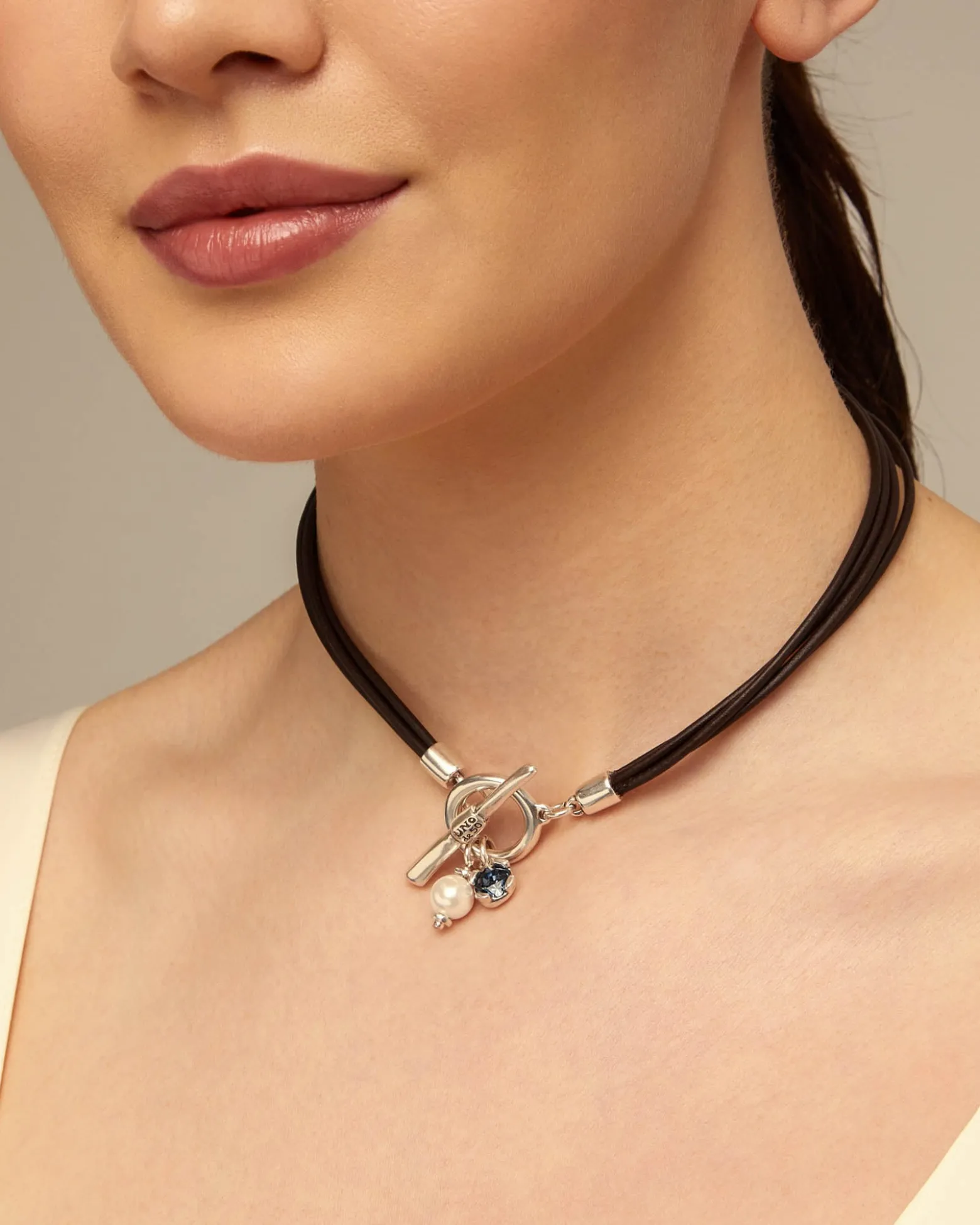 Collar de cuero con cierre central con charm de perla y cristal.