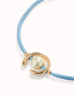 Pulsera de hilo azul con perla shell fornitura bañada en oro 18k.