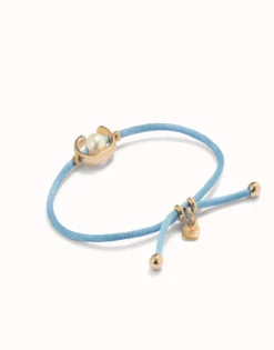 Pulsera de hilo azul con perla shell fornitura bañada en oro 18k.