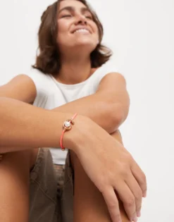 Pulsera de hilo fucsia con perla shell fornitura bañada en oro 18k.