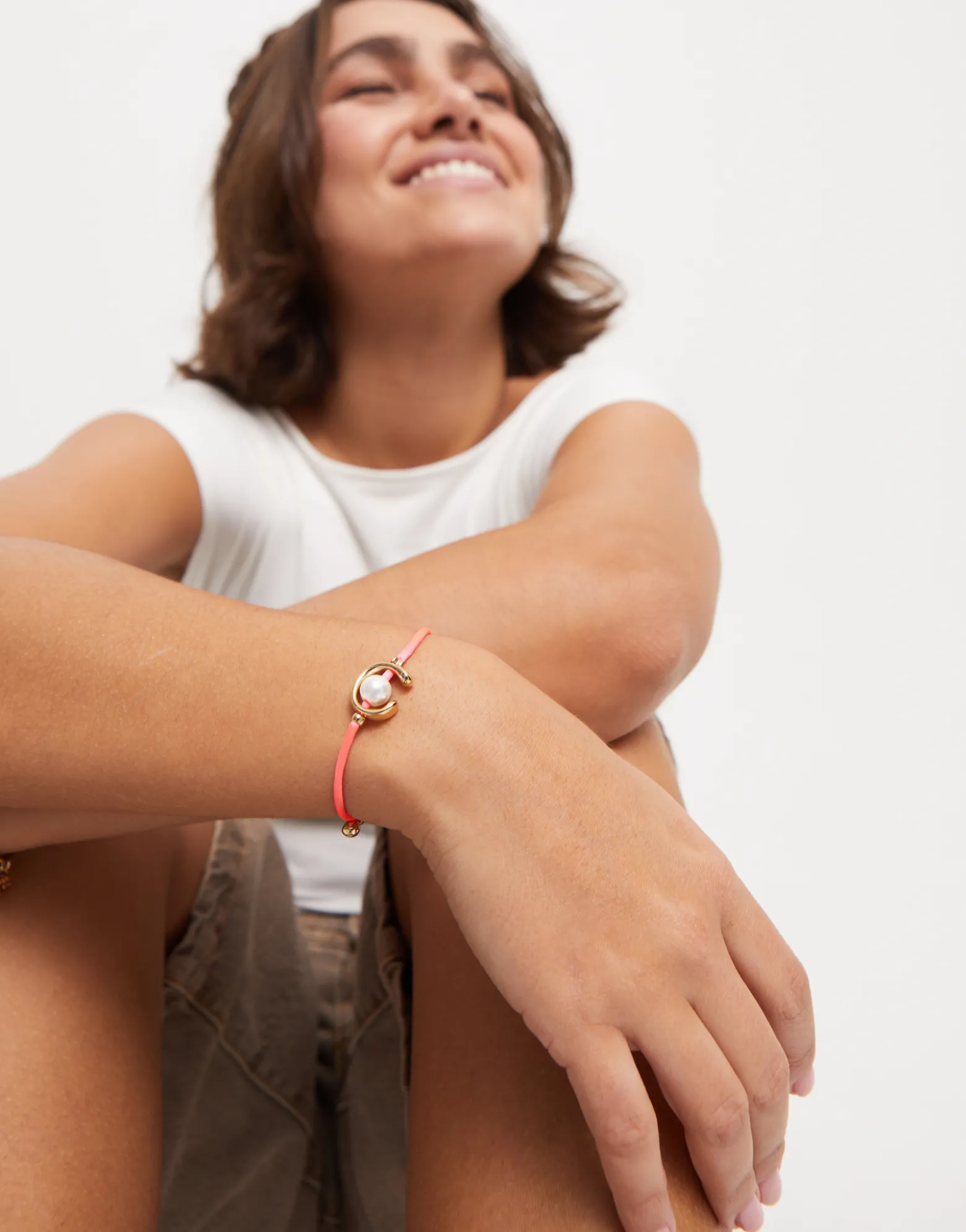 Pulsera de hilo fucsia con perla shell fornitura bañada en oro 18k.