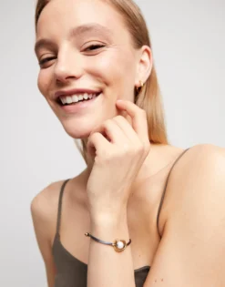 Pulsera de hilo negroso con perla shell fornitura bañada en oro 18k.