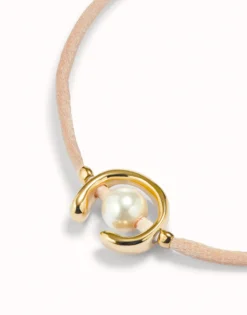 Pulsera de hilo salmón con perla shell fornitura bañada en oro 18k.