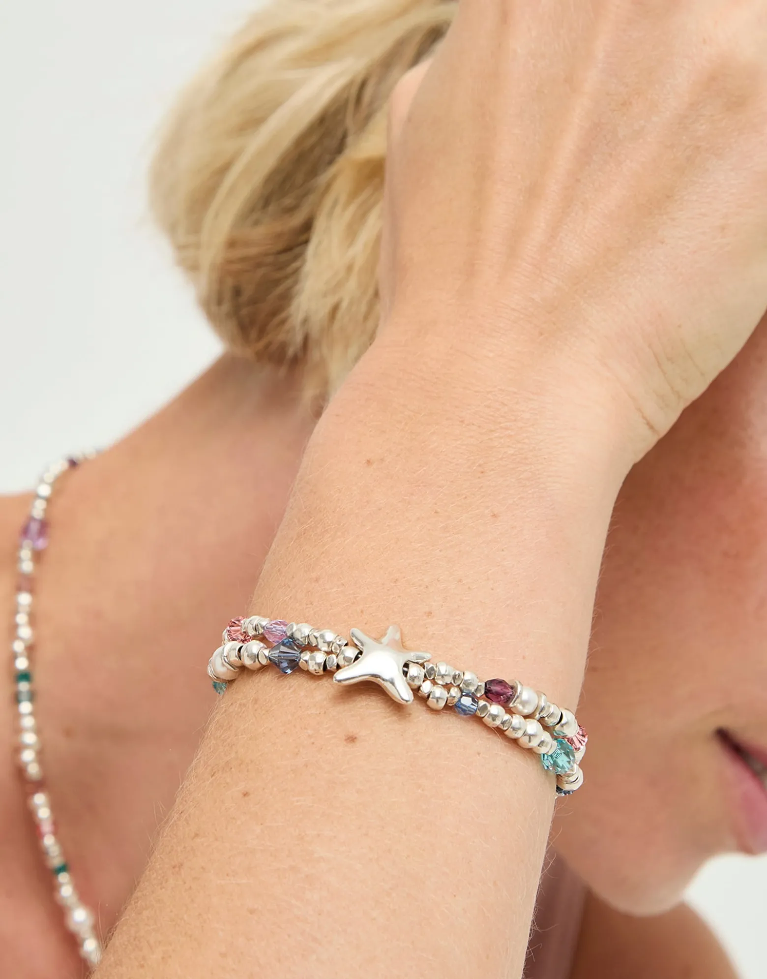 Pulsera elástica bañada en plata con cristales facetados y estrella de mar