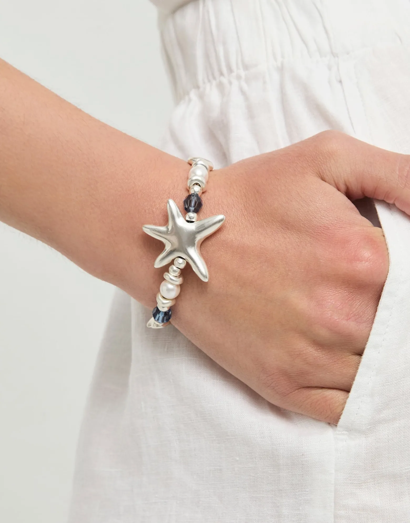 Pulsera elástica bañada en plata con cristales azules y estrella de mar